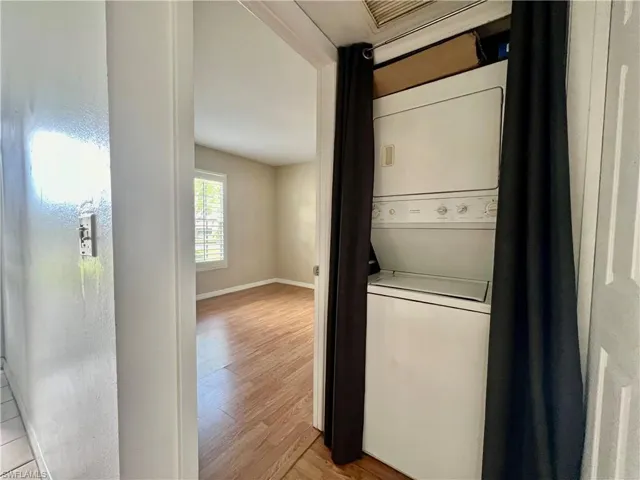 Laundry area featuring light wood-type flooring and stacked washer / dryer