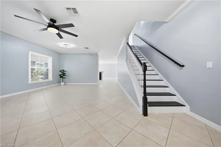 Spacious room featuring neutral tile flooring, light blue wall paint, and white baseboards