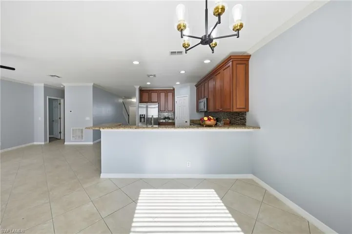 Open-concept living space featuring a kitchen with wood cabinetry, stainless steel appliances, and a stone countertop