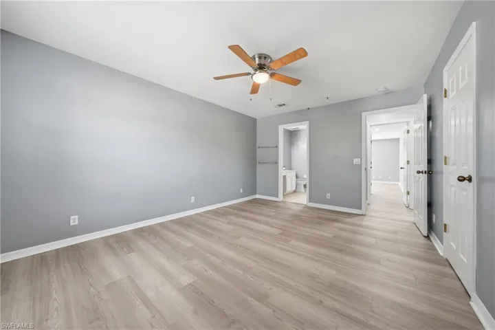 Spacious interior room featuring wood-finish flooring, light gray wall tones, and white baseboards
