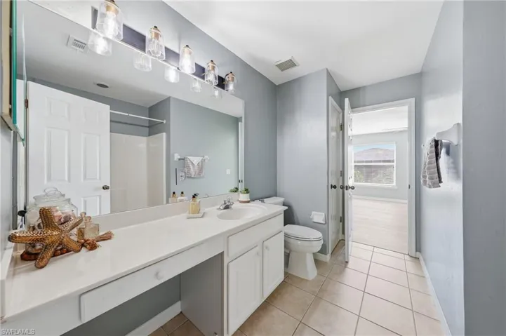 Bathroom featuring a single vanity with an integrated sink, ample counter space, and white cabinetry