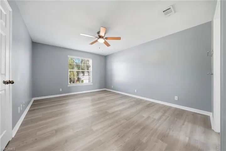 Spacious room featuring wood-finish flooring and a ceiling fan with integrated lighting