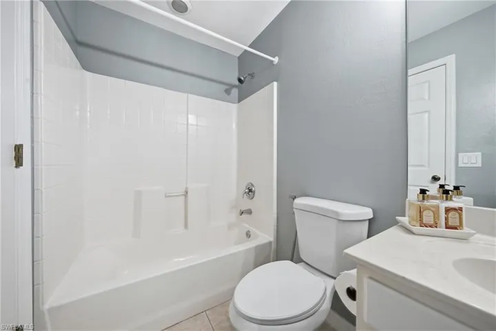 Full bathroom featuring a white tub/shower combination, white toilet, and a white single-sink vanity with an integrated countertop