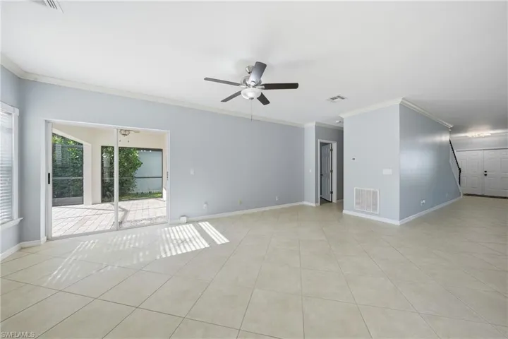 Spacious interior featuring neutral tile flooring, light blue wall paint, and white crown molding