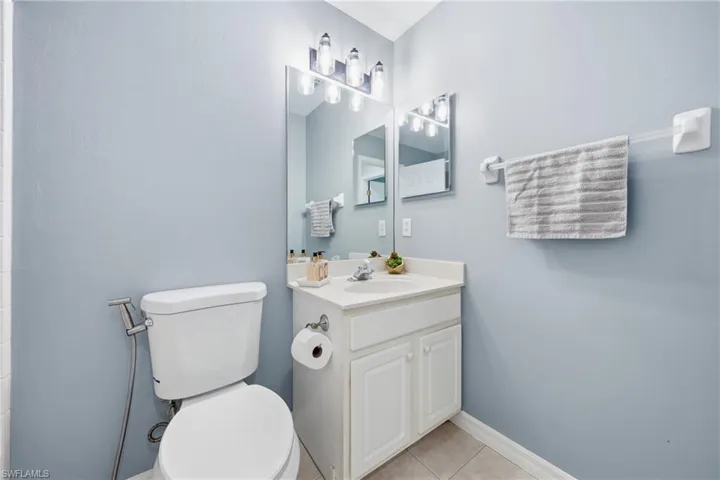 Bathroom featuring a white vanity with an integrated sink, a wall-mounted mirror, and vanity lighting