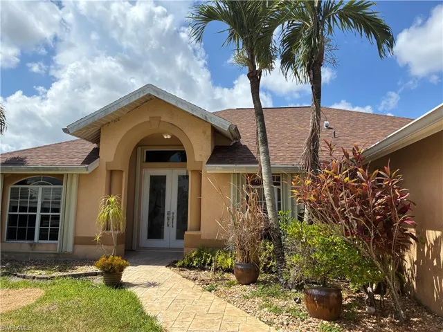 Front entry featuring double glass doors, arched portico, and decorative columns