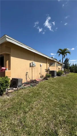 Stucco exterior with multiple HVAC units and a manicured lawn