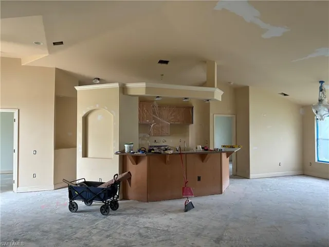 Open-concept living space with a kitchen island, recessed lighting, and a decorative arch niche