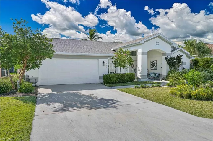View of front of property featuring driveway, stucco siding, a front lawn, and a garage