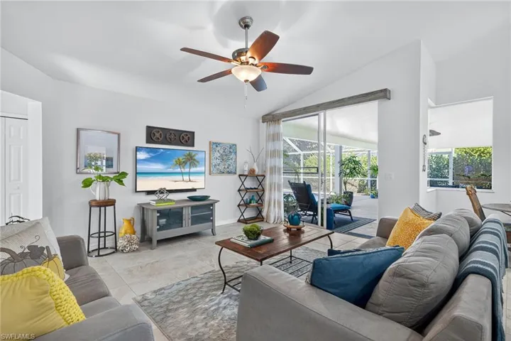 Tiled living room featuring a ceiling fan and lofted ceiling