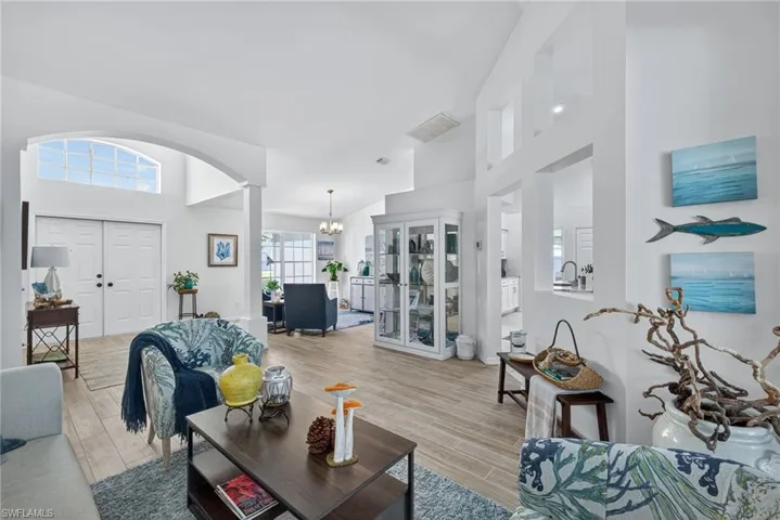 Living room featuring light wood-style flooring, hanging lights, and vaulted ceiling
