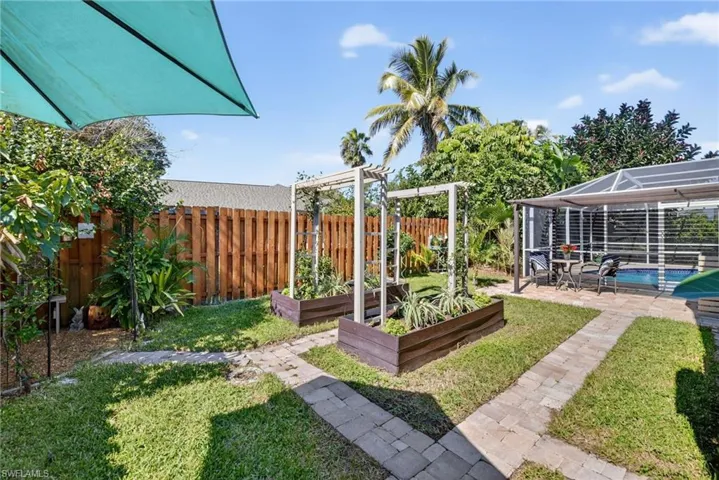 Fenced backyard featuring a garden, a patio area, and a lanai