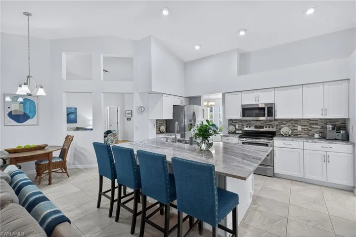 Kitchen featuring a chandelier, a breakfast bar area, white cabinetry, stainless steel appliances, and tasteful backsplash