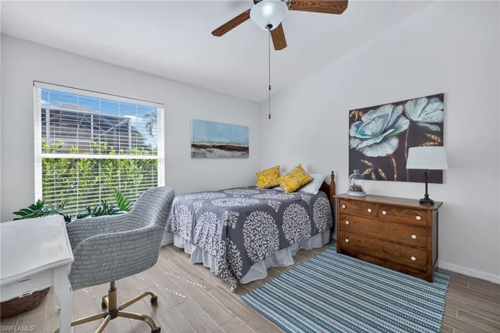 Bedroom featuring vaulted ceiling, wood finished floors, and a ceiling fan