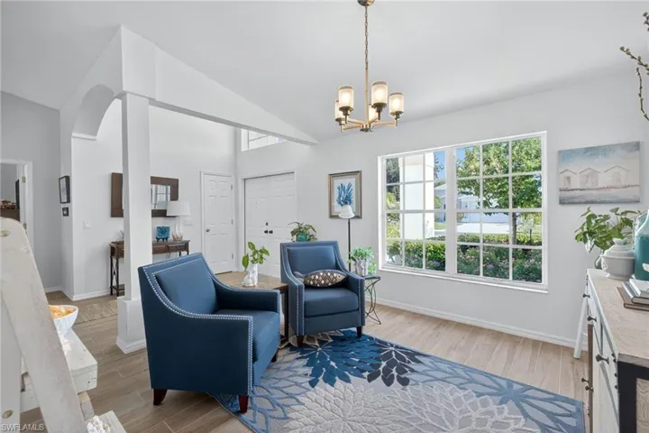 Sitting room featuring light wood finished floors, lofted ceiling, hanging lights, and arched walkways