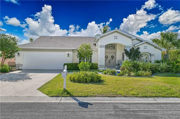 View of front of property with a front yard, driveway, a garage, stucco siding, and roof with shingles