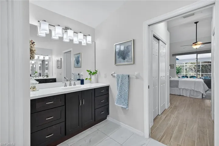 Ensuite bathroom featuring vanity, a ceiling fan, and a closet