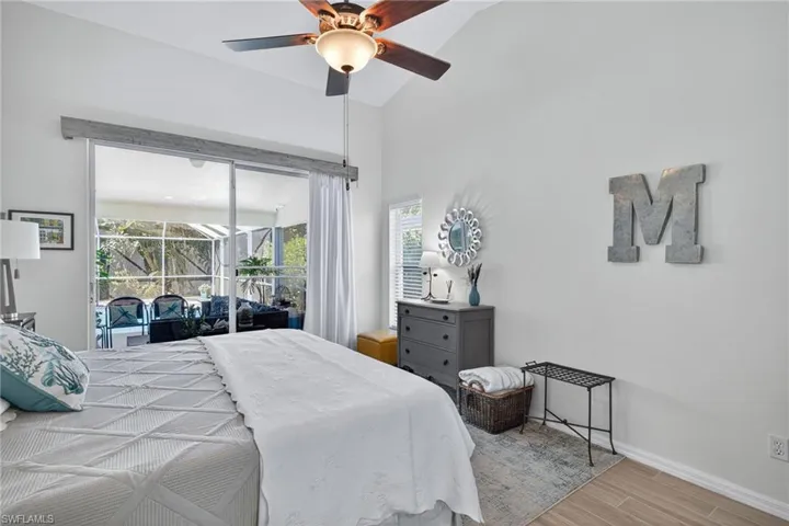Bedroom with a sunroom, wood finish floors, access to outside, ceiling fan, and lofted ceiling