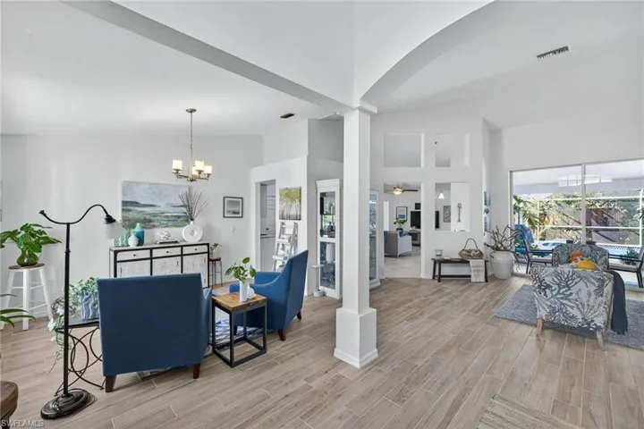 Living area with lofted ceiling, wood finish floors, suspended lighting, and a ceiling fan