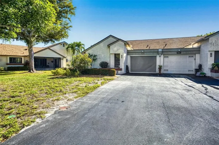 View of front of property featuring driveway, a garage, stucco siding, and a front lawn