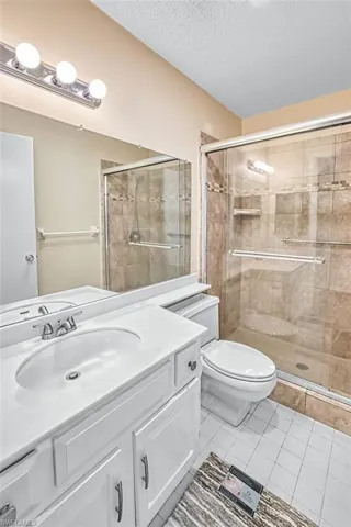 Bathroom featuring vanity, light tile patterned floors, a textured ceiling, and a shower stall
