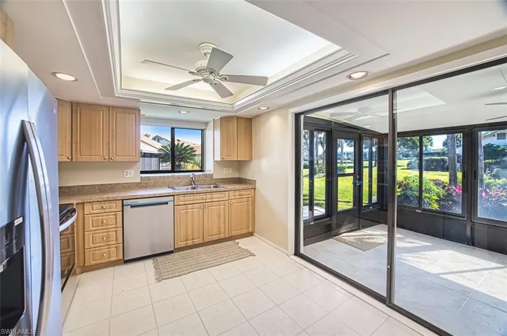 Kitchen with a tray ceiling, a ceiling fan, stainless steel appliances, light tile patterned flooring, and recessed lighting