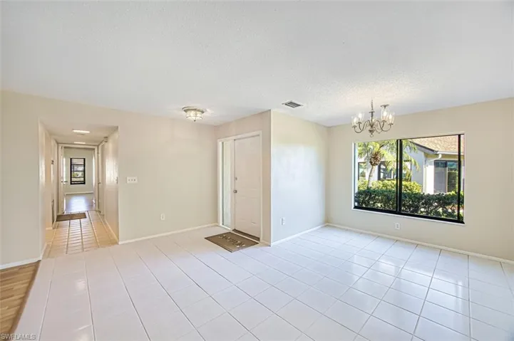Spare room with a chandelier, a textured ceiling, and light tile patterned floors