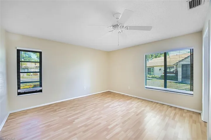 Spare room featuring light wood finished floors, plenty of natural light, a ceiling fan, and a textured ceiling