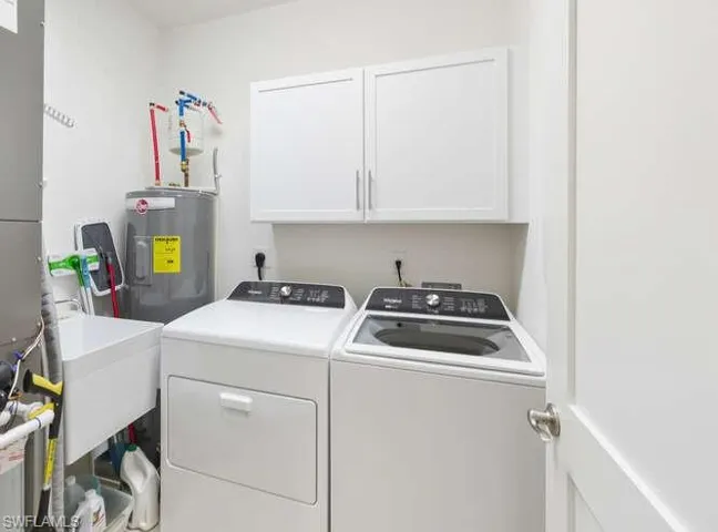Washroom featuring separate washer and dryer, water heater, cabinet space, and heating unit