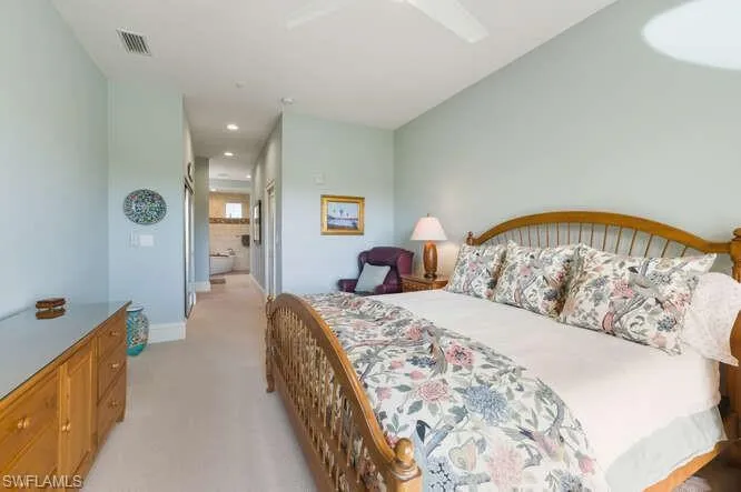 Bedroom featuring a closet, light carpet, ceiling fan, and ensuite bath