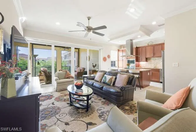 Living area with a raised ceiling, a ceiling fan, crown molding, and recessed lighting
