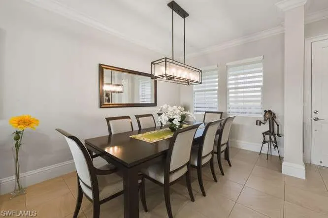 Dining space with crown molding and light tile patterned flooring
