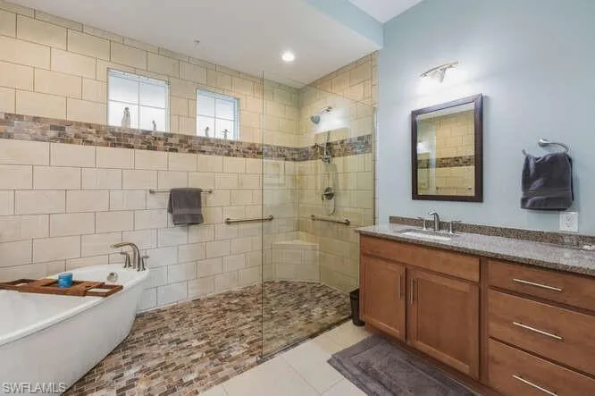Full bath featuring vanity, light tile patterned floors, a soaking tub, a walk in shower, and recessed lighting