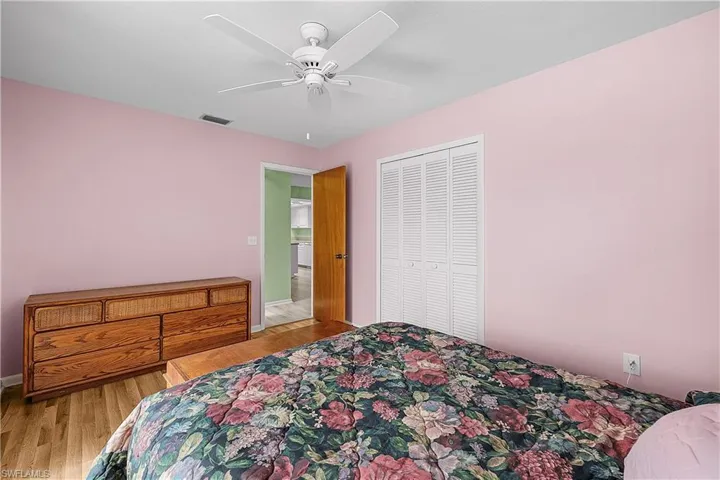 Bedroom with visible vents, wood finished floors, a closet, baseboards, and ceiling fan