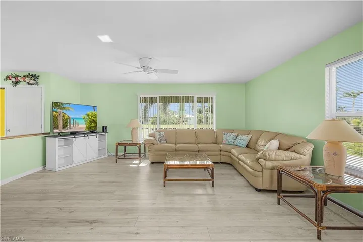 Living room with a wealth of natural light, baseboards, a ceiling fan, and light wood finished floors