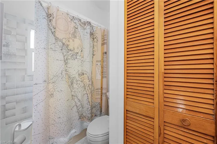 Bathroom with a closet, toilet, and a shower with curtain