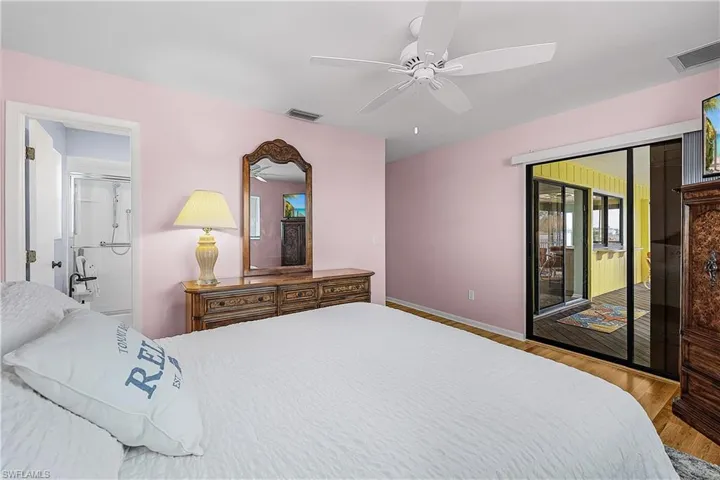 Bedroom with visible vents, wood finished floors, a ceiling fan, and access to outside