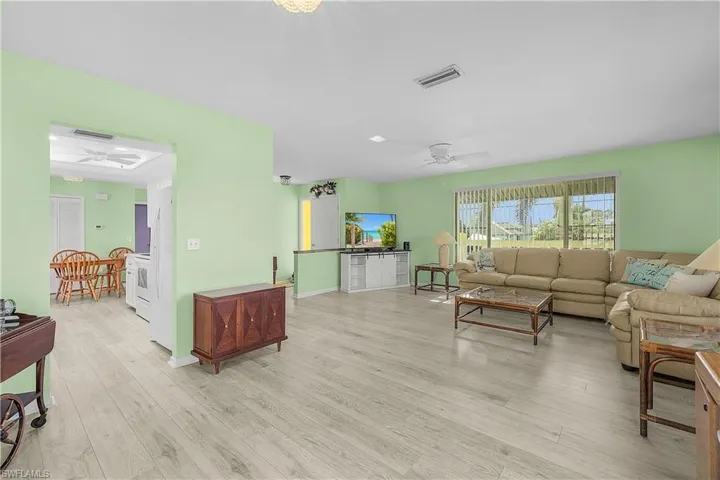 Living area with light wood-type flooring, visible vents, and ceiling fan