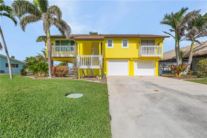 Coastal home with driveway, a front yard, and a garage