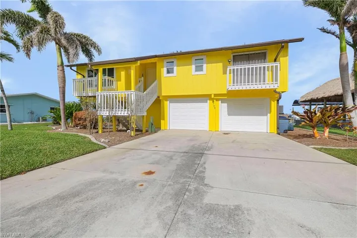 Waterfront home with concrete driveway, an attached garage, and a front yard