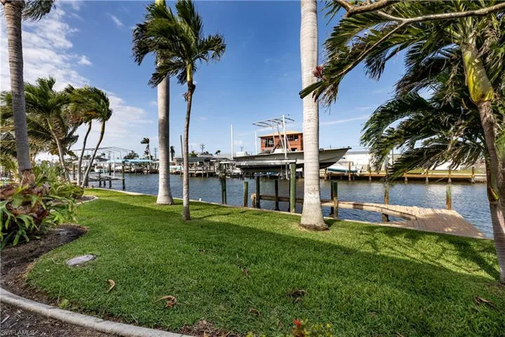 View of dock with a water view, boat lift, and a lawn