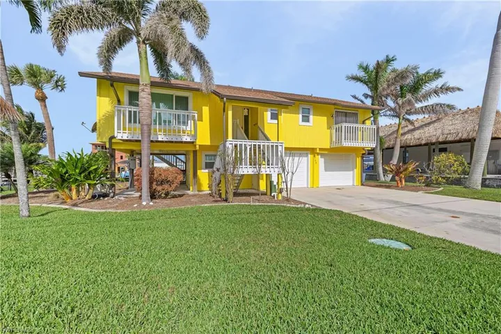 Coastal inspired home with a garage, driveway, a balcony, and a front yard