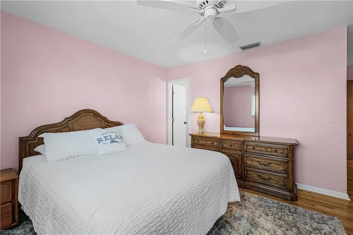 Bedroom with visible vents, a ceiling fan, baseboards, and wood finished floors