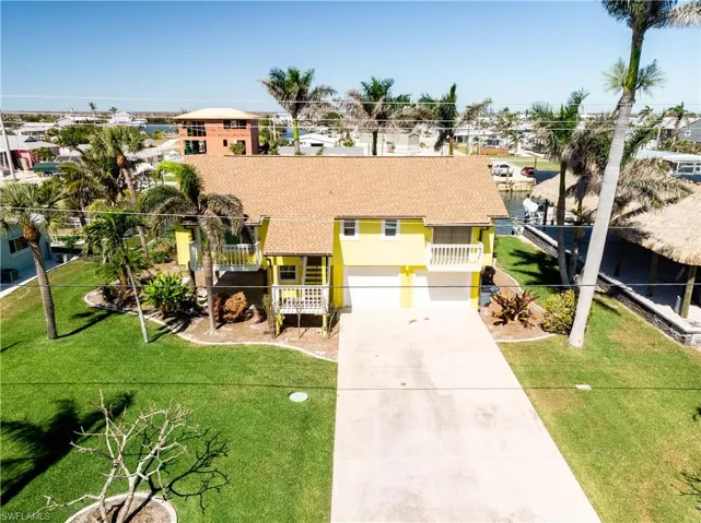 View of front of home with a front yard, an attached garage, driveway, and a shingled roof