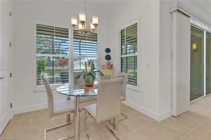 Tiled dining space featuring crown molding, a healthy amount of sunlight, and a notable chandelier