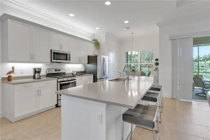 Kitchen with crown molding, appliances with stainless steel finishes, a breakfast bar, and an island with sink