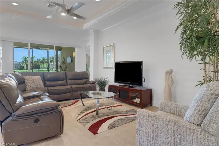Living room with ceiling fan, ornamental molding, and light tile patterned floors