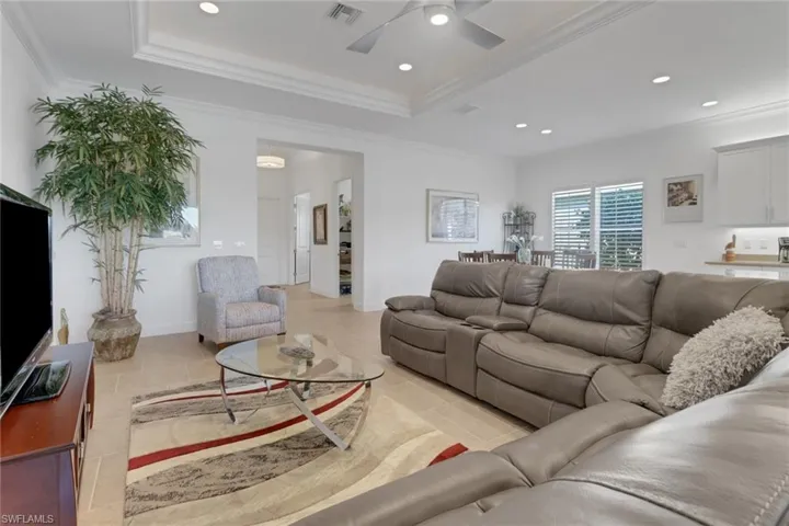 Living room featuring a tray ceiling, ornamental molding, and ceiling fan
