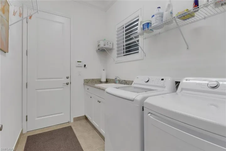 Laundry room with cabinets, sink, light tile patterned floors, and independent washer and dryer