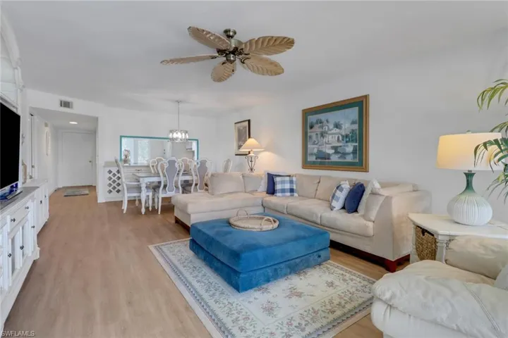 Living area with ceiling fan with notable chandelier, light wood-type flooring, and visible vents